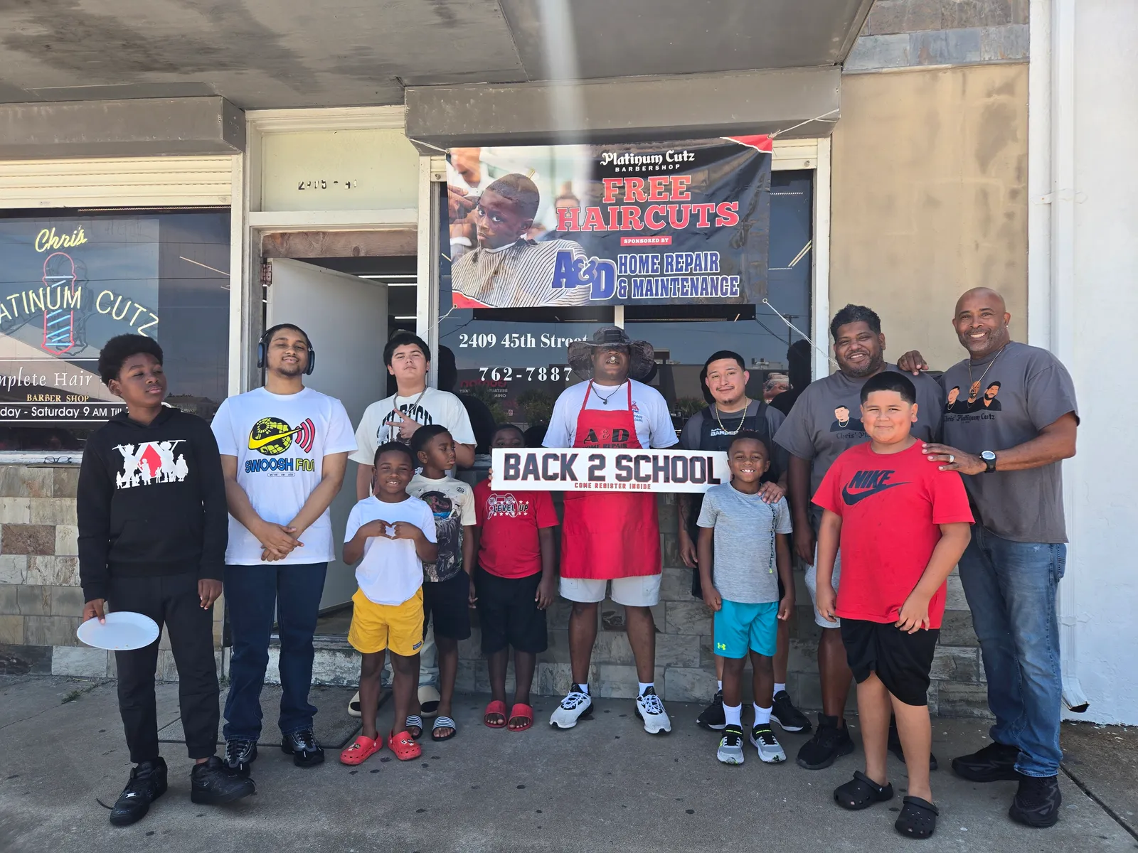 Chris, community partners, and children at the annual free back-to-school haircut event